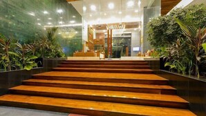 L’entrée d’un hôtel moderne, avec un escalier en bois menant à l’accueil.