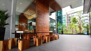 A modern lobby with wooden furniture, a central column, and a view of the outside. - Nice Residence Hotel Huahin (Hua Hin)