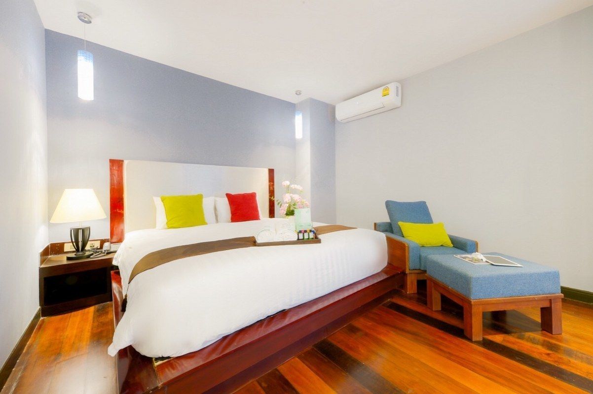 A hotel room with a bed, a nightstand, a lamp, a chair, and a window.