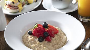 A bowl of oatmeal with strawberries and blueberries on a white plate.