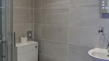 A bathroom with a toilet, sink, and shower.
