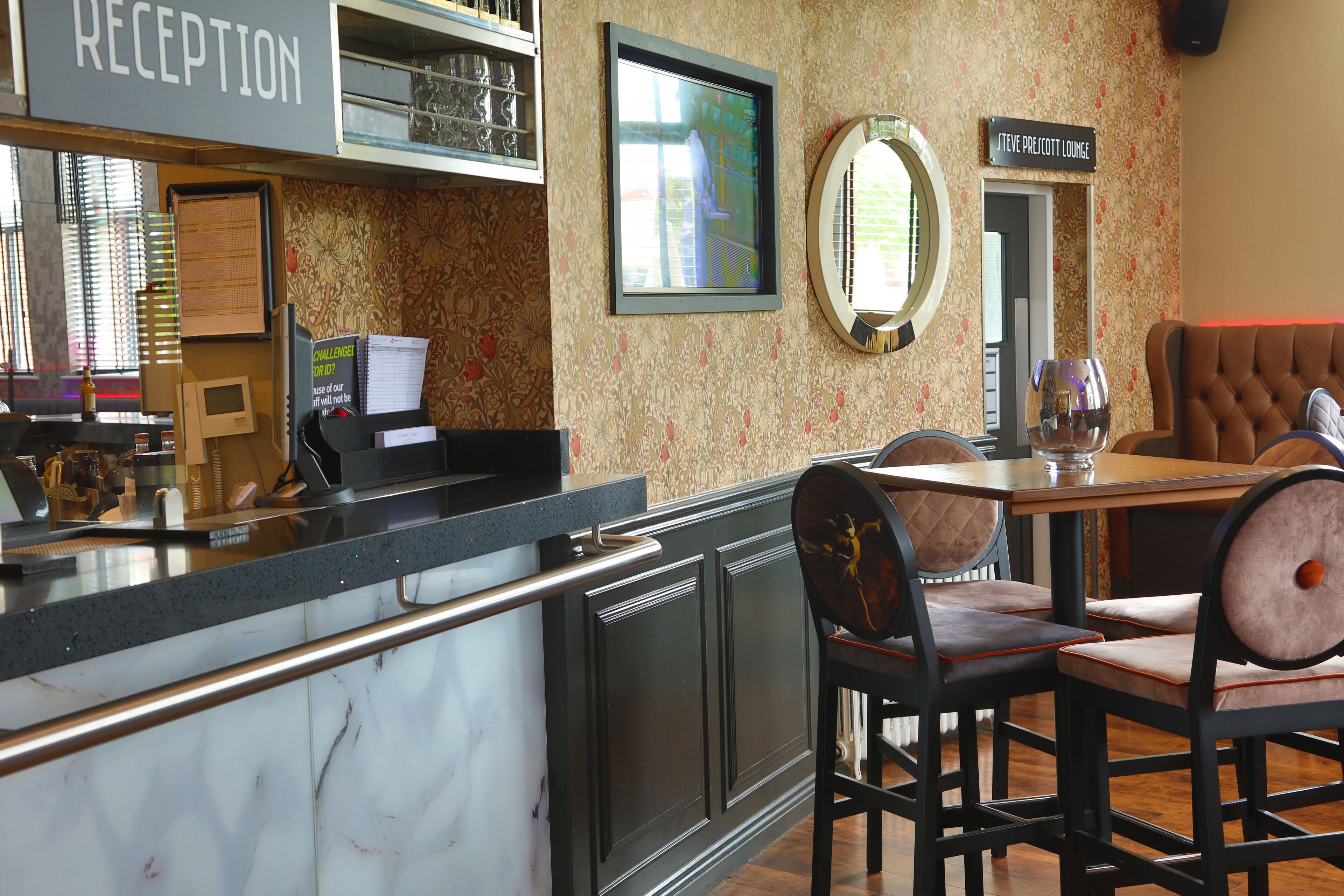 A reception area with a marble counter, a reception desk, and a seating area with cushioned chairs and a table.