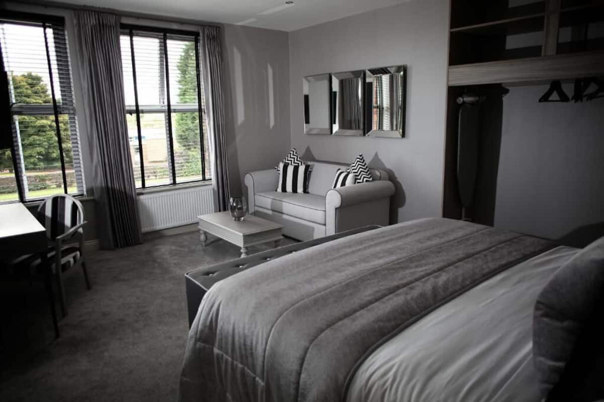 A bedroom with a bed, a sofa, a coffee table, and a desk.
