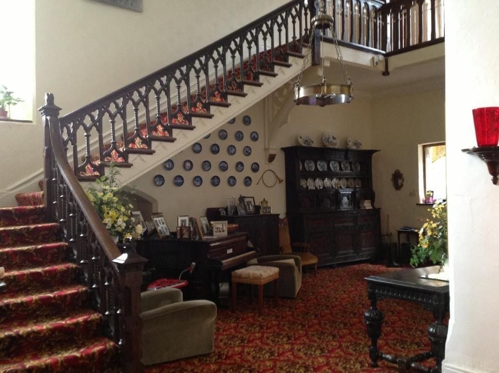 A staircase with a dark railing, a patterned carpet, and a wall adorned with plates.