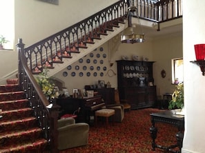 Un escalier avec une rampe sombre, une moquette à motifs et un mur décoré d’assiettes.