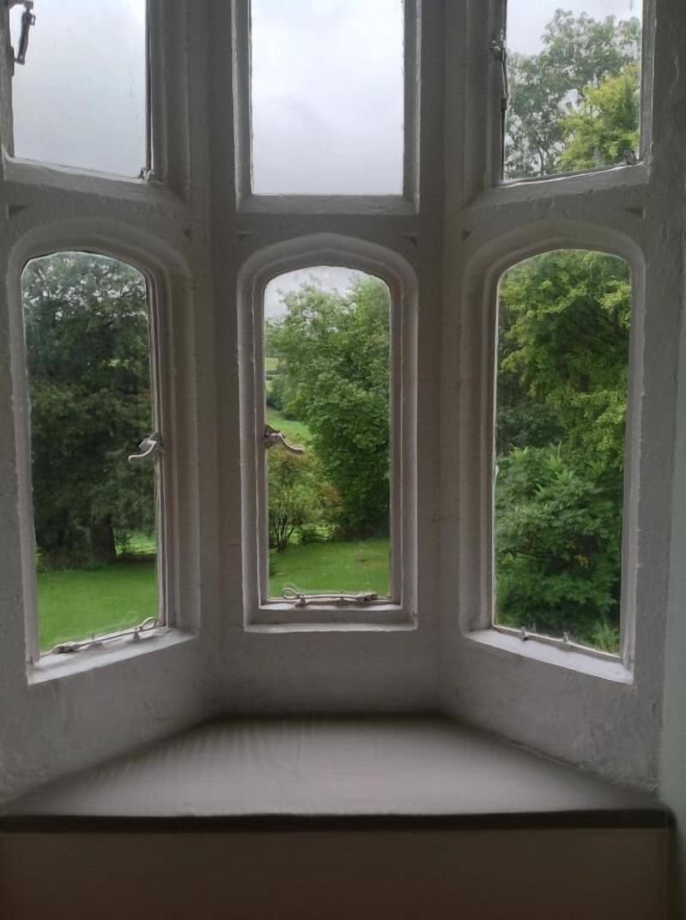 A room with a bay window overlooking a garden.