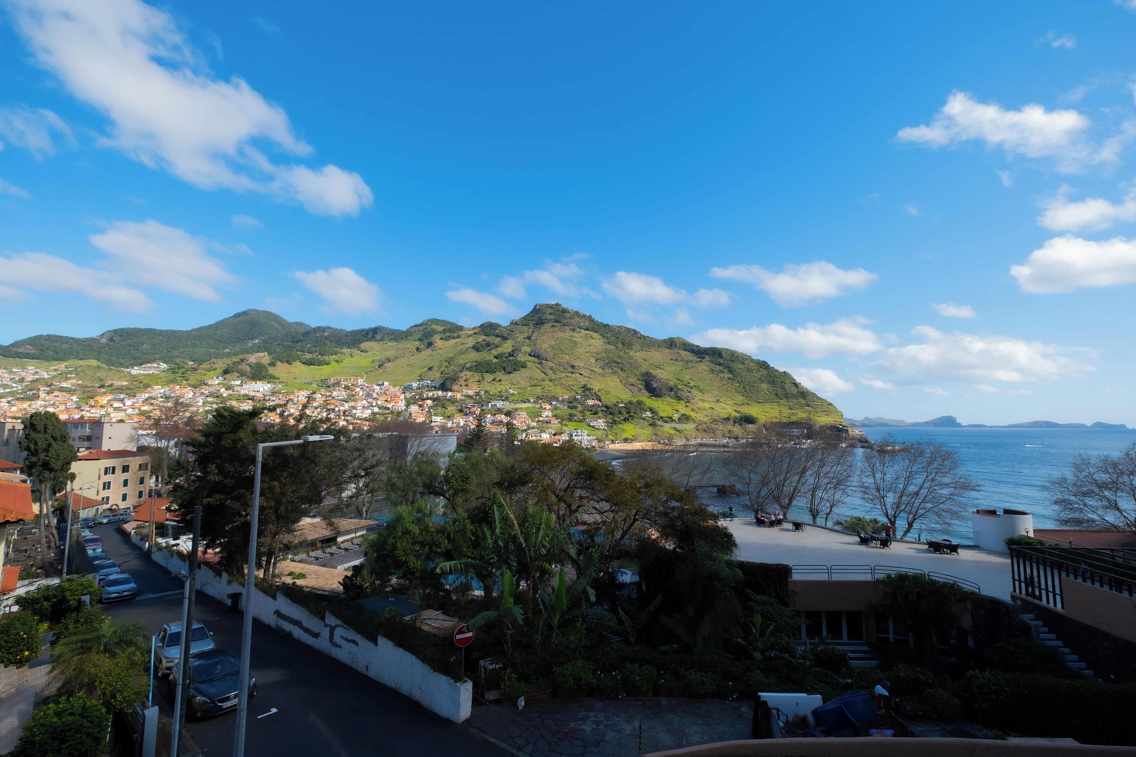 Un pueblo costero con vista al mar y colinas al fondo.