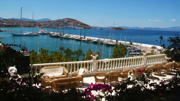 A marina with boats docked, a white railing, and outdoor seating with cushions. - Kismet Hotel (Kusadasi)