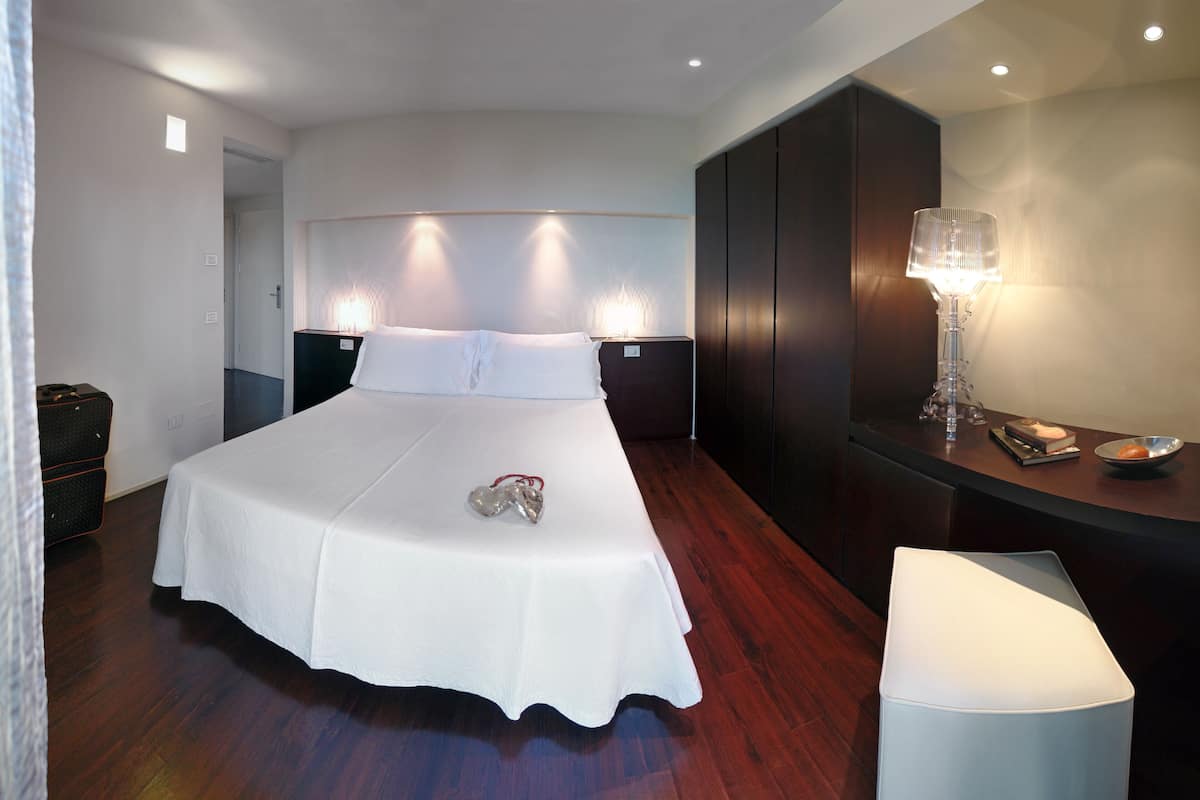 Een moderne hotelkamer met een groot bed, nachtkastjes, een bureau en een lamp.