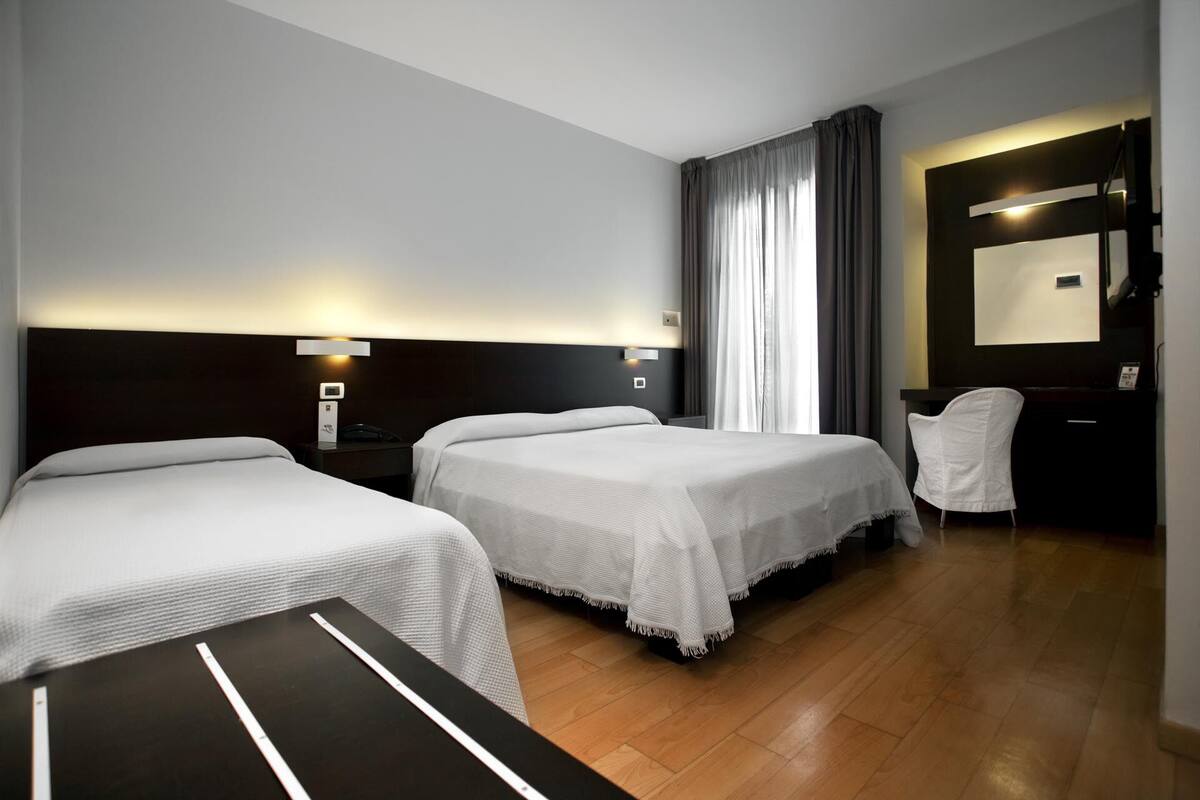 Een hotelkamer met twee bedden, een bureau, een stoel en een spiegel.