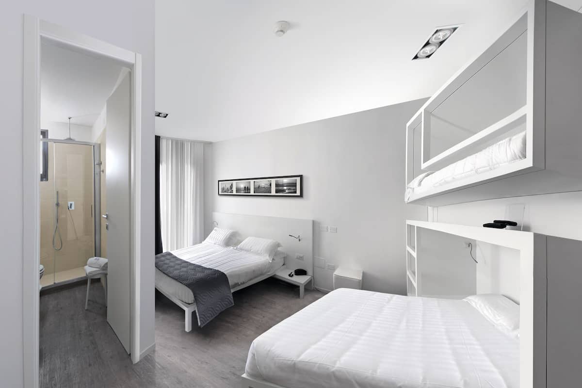 Een moderne slaapkamer met twee bedden, een inloopkast en een douchegedeelte.
