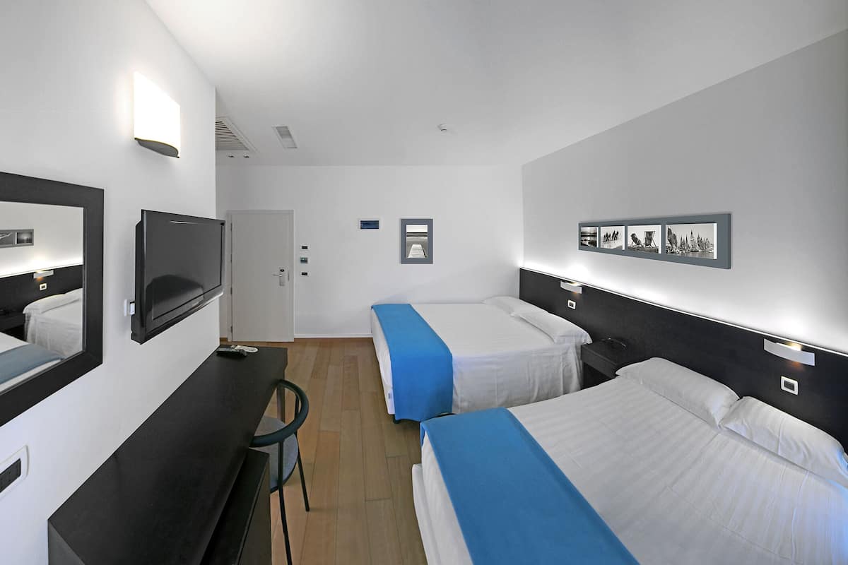 Een hotelkamer met twee bedden, een bureau, een stoel, een televisie en een deur.
