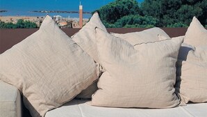 A rooftop terrace with beige cushions and a view of the sea and a lighthouse. - Hotel Europa Monetti (Cattolica)