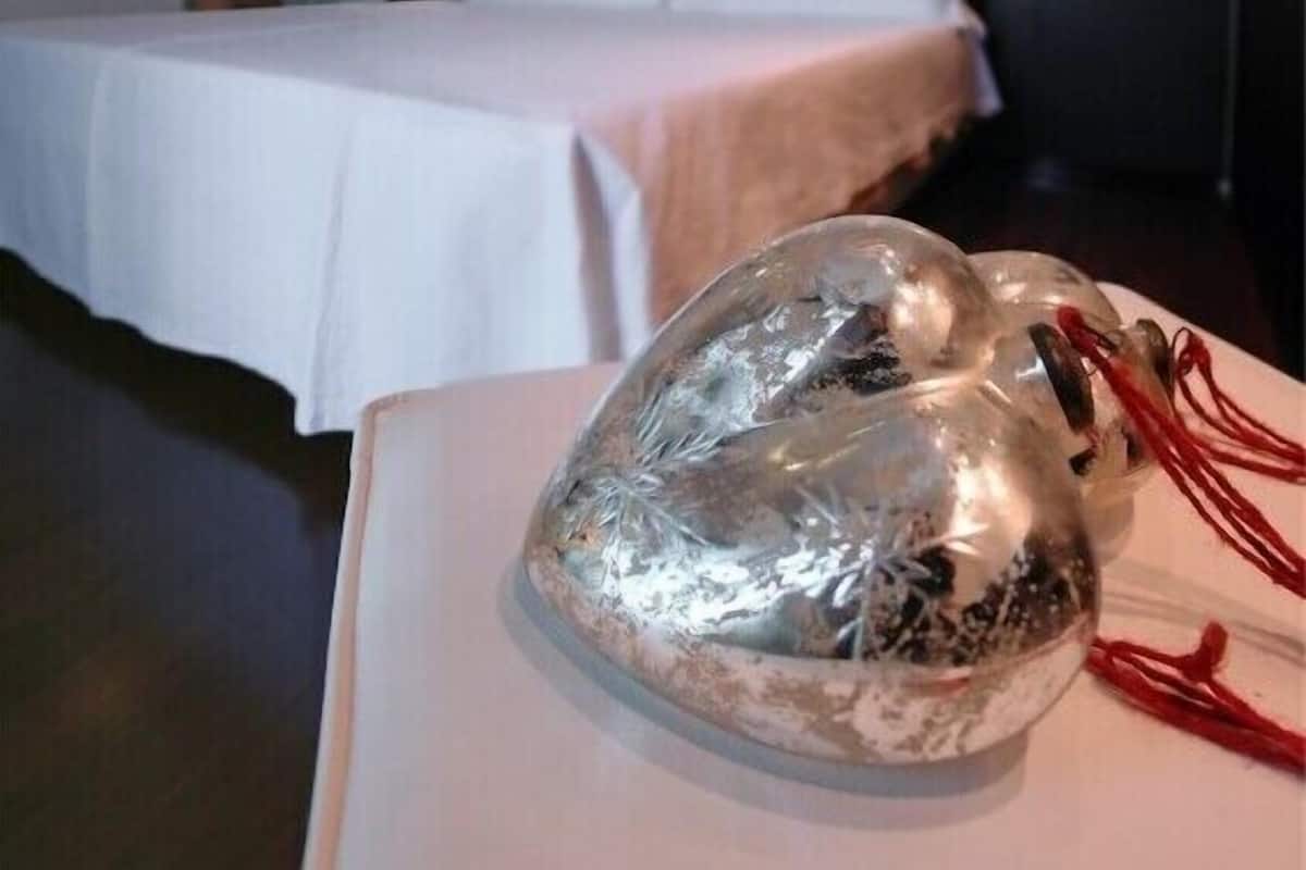 Een hotelkamer met een bed, nachtkastje en een decoratief object op het tafeltje.