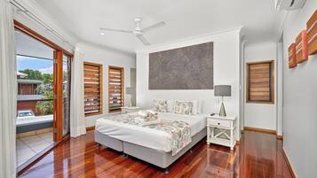 A spacious bedroom with a large bed, a ceiling fan, and a view of the outdoors.