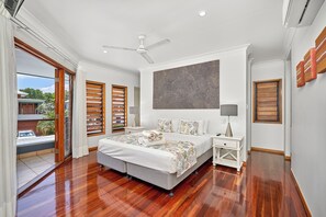 Un dormitorio amplio con una cama grande, un ventilador de techo y vistas al exterior.