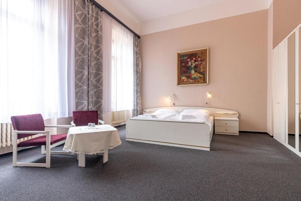Een hotelkamer met een bed, een bureau met stoel, een tafel en een schilderij aan de muur.