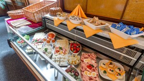 Ein reichhaltiges Buffet mit verschiedenen Speisen, darunter Obst, Käse, Fleisch und Brot.