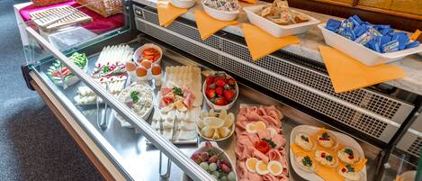 A buffet with various food items including fruits, cheeses, meats, and breads.