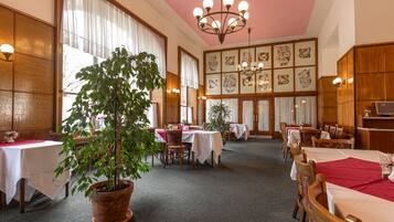A dining area with multiple tables, chairs, and potted plants.