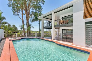 Enjoy a relaxing stay in this two-story home with a balcony and pool surrounded by lush greenery.