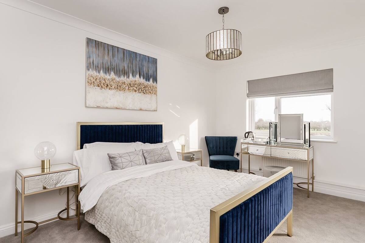 A bedroom with a bed, bedside tables, a desk, a chair, a window, and a ceiling light.