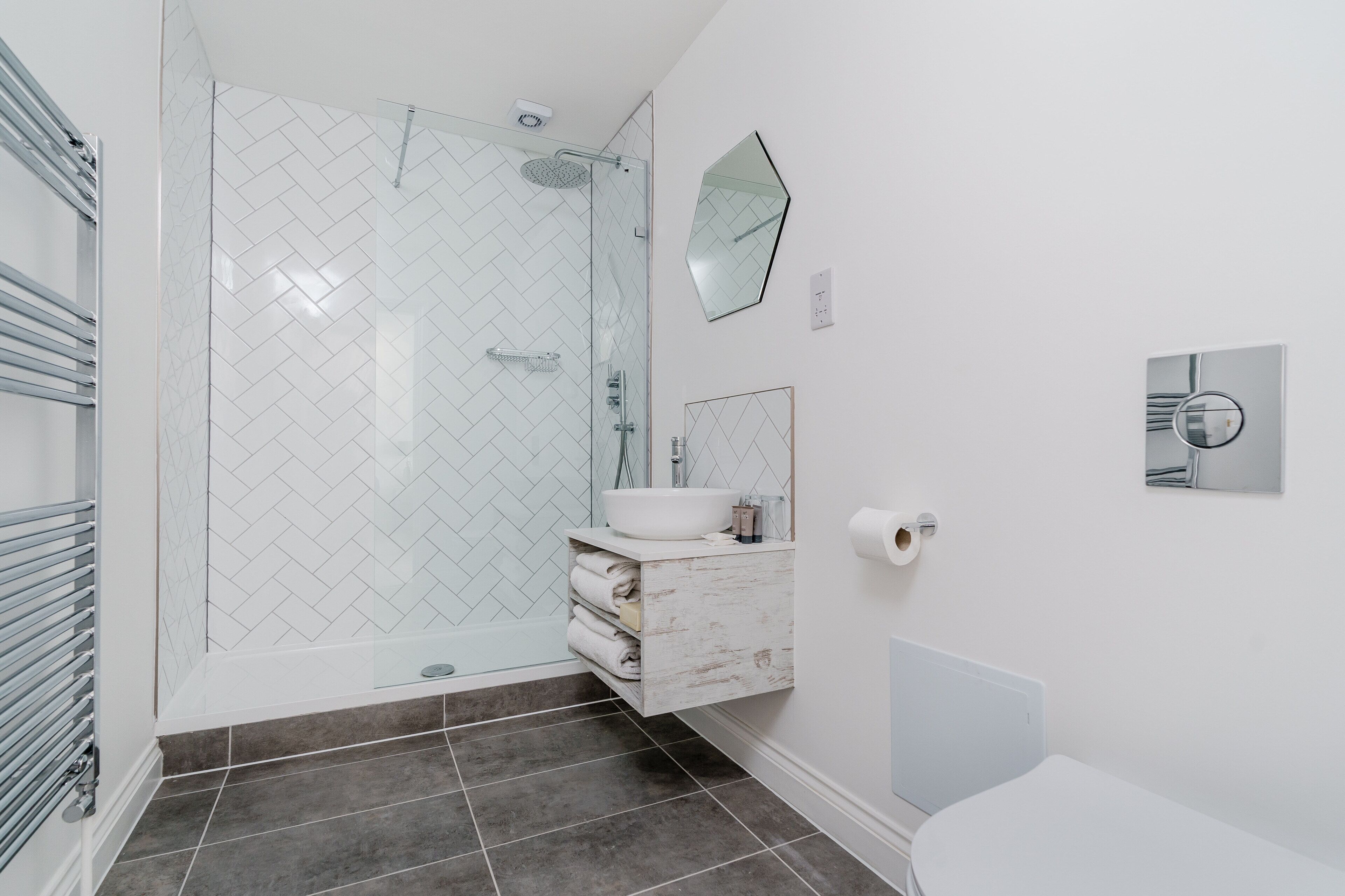 Un baño moderno con ducha de vidrio, tocador blanco y retrete.