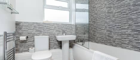 A modern bathroom with a toilet, sink, and shower.