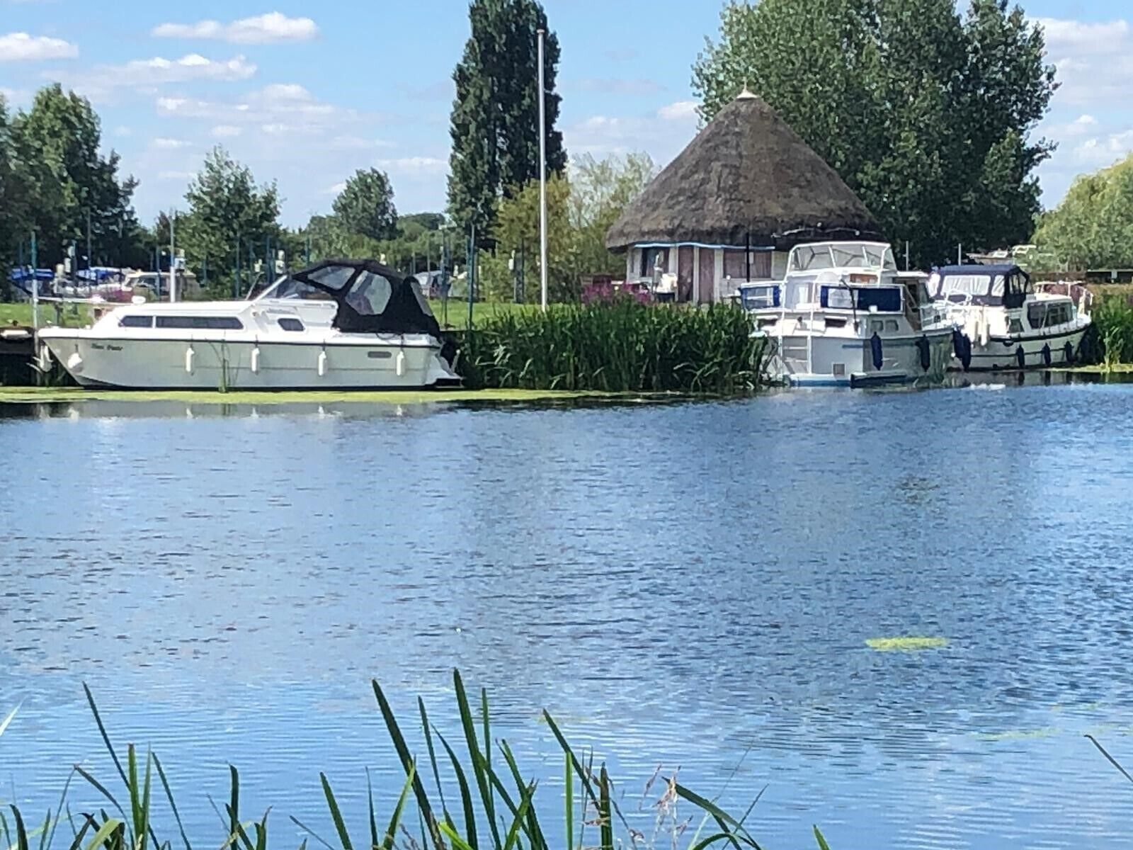 A calm river with boats docked on the shore.