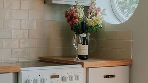A kitchen with a white stove, a white oven, a wooden countertop, and a vase with flowers and a wine bottle. - Pine Tree Lodge Bridgnorth (Bridgnorth)