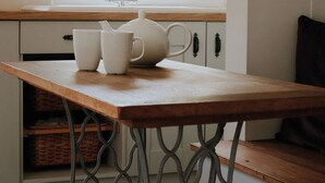A kitchen with a wooden table, white teapot, and two white cups. - Pine Tree Lodge Bridgnorth (Bridgnorth)