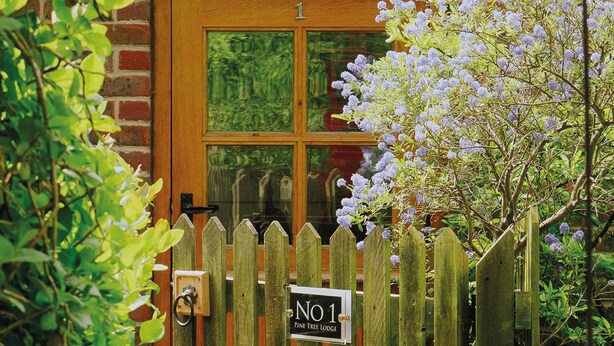 A wooden door with a window, a sign reading "No 1 Pine Tree Lodge", and a wooden fence with a gate. - Pine Tree Lodge Bridgnorth (Bridgnorth)