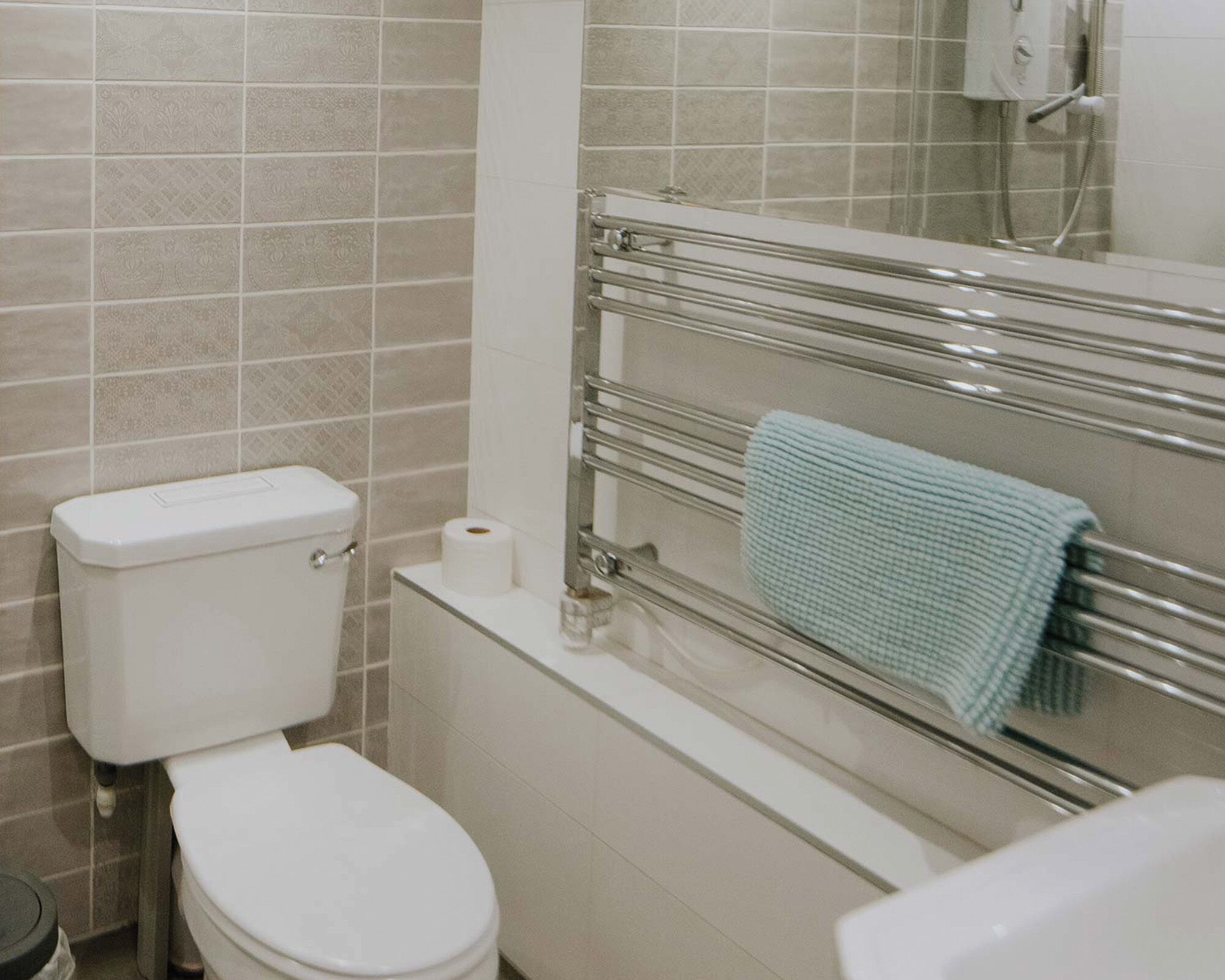 A bathroom with a toilet, a towel rack, and a shower area.
