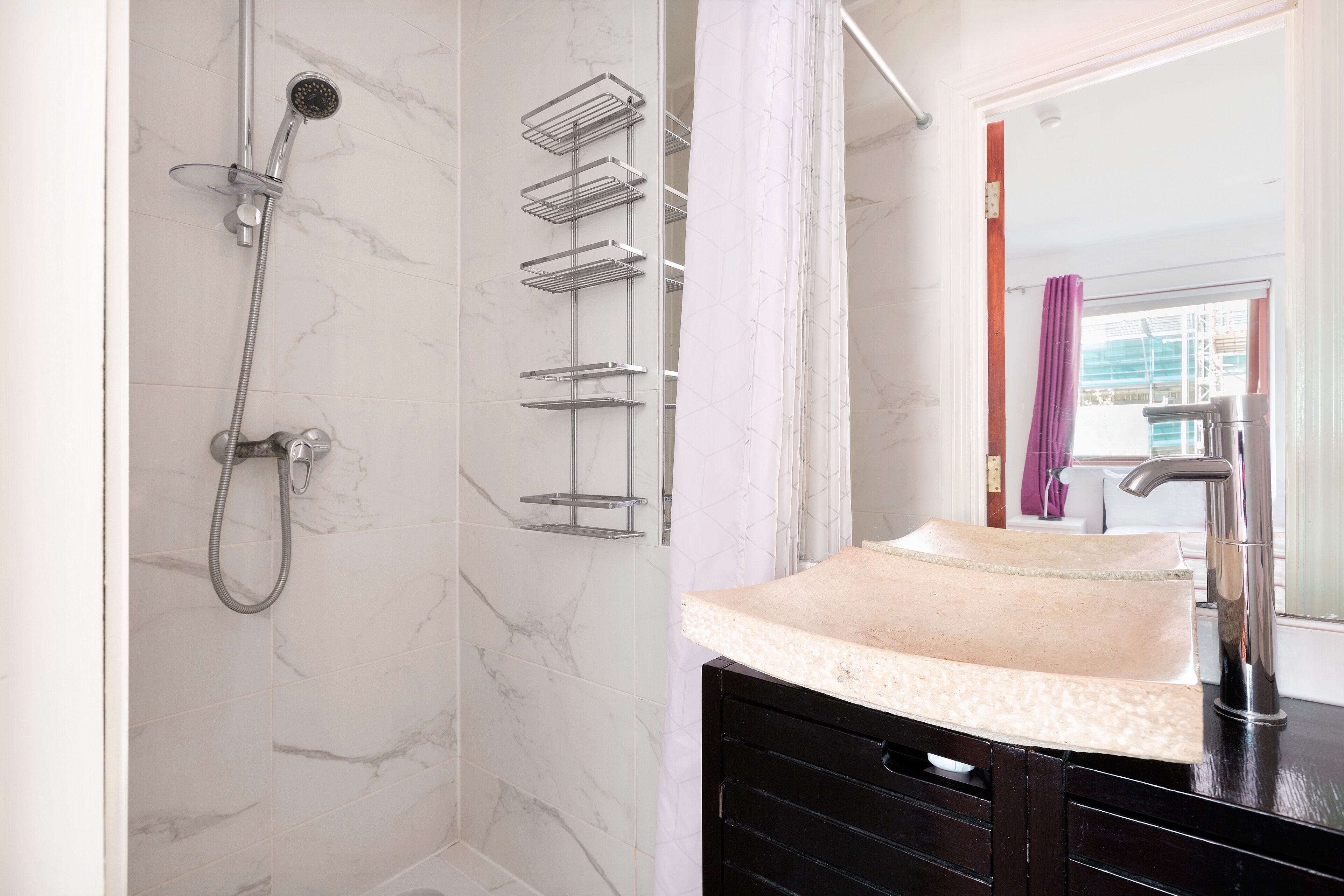 A bathroom with a shower, a sink, and a mirror.