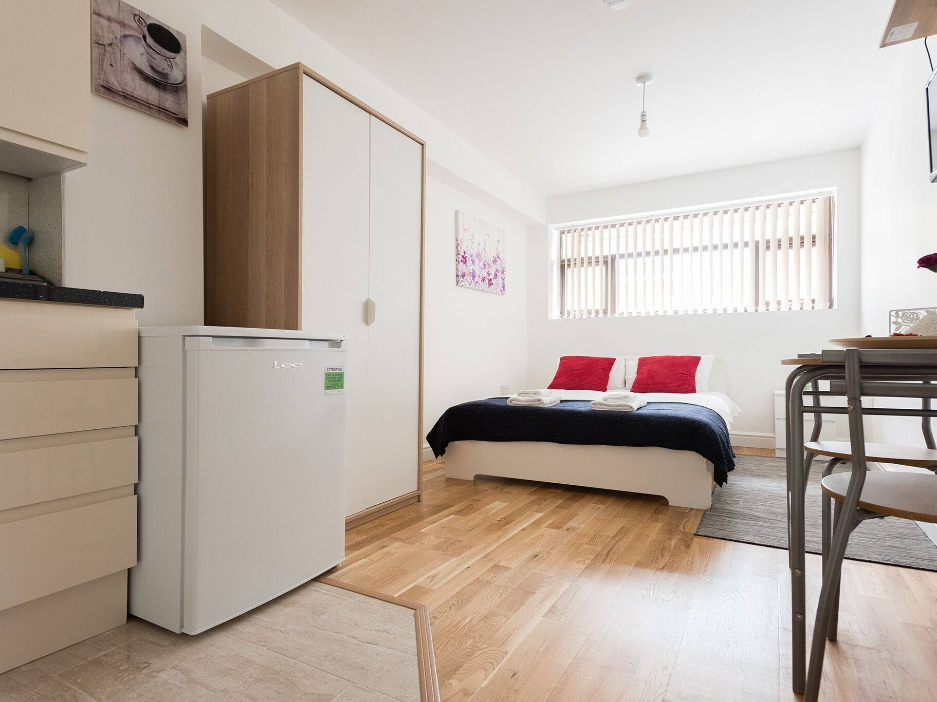 A compact room with a bed, a small kitchenette, and a dining area.