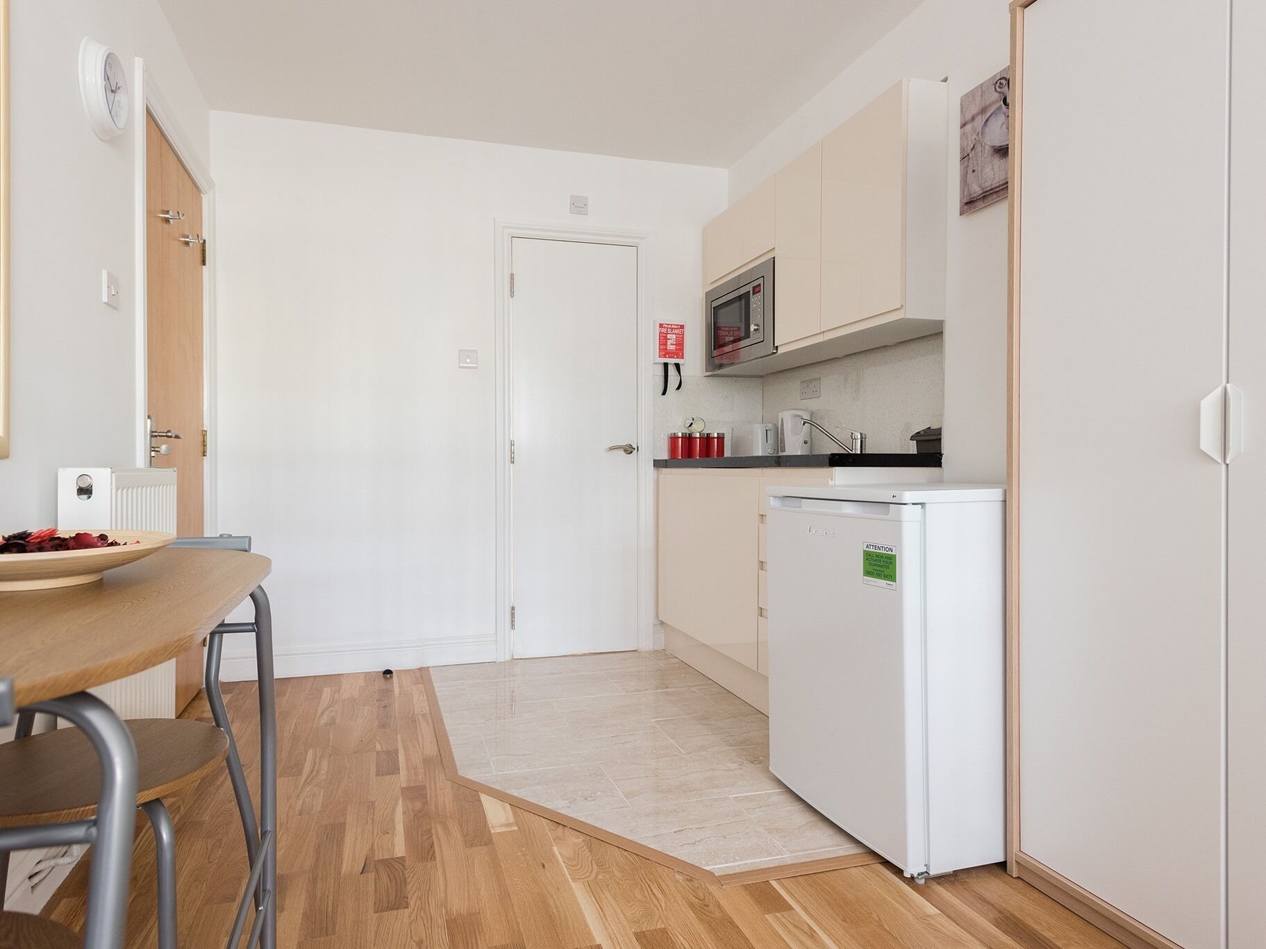 Een kleine keuken met een magnetron, een koelkastje en een spoelbak.
