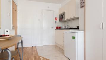 Een kleine keuken met een magnetron, een koelkastje en een spoelbak.