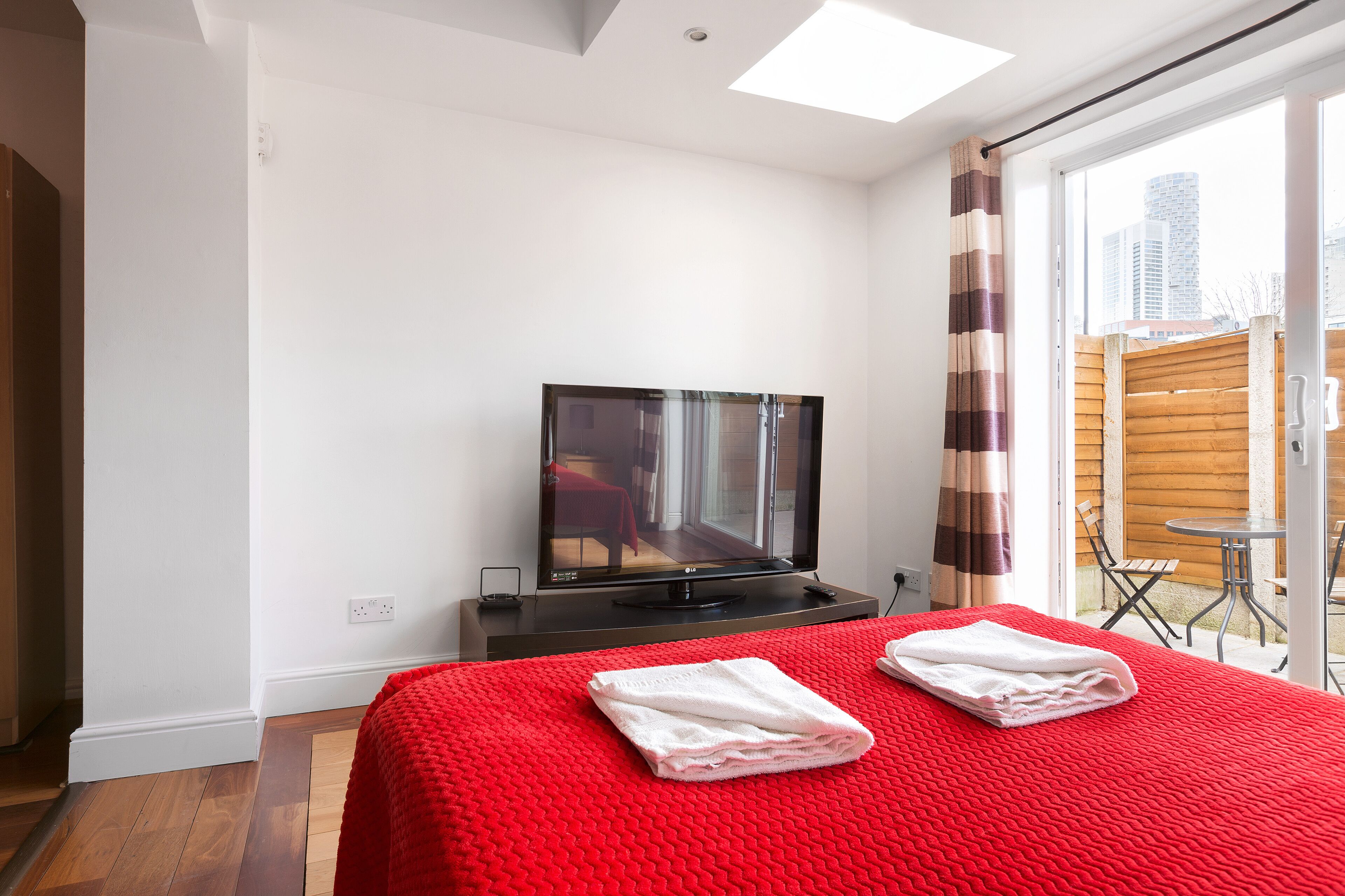Une chambre d’hôtel avec un grand lit, une télévision et une vue sur la ville par la fenêtre.