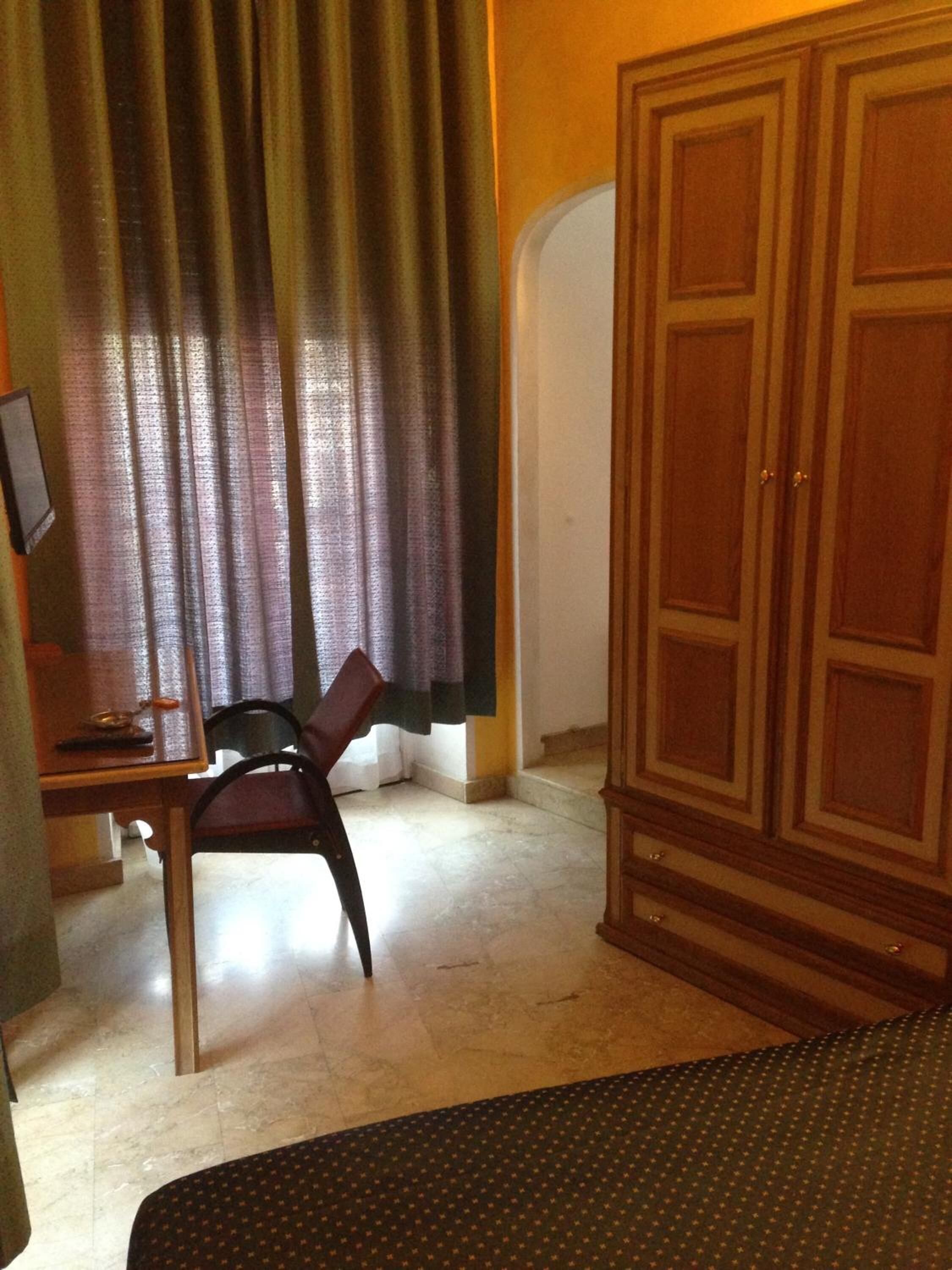 A room with a desk, chair, wardrobe, and a bed.