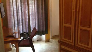 A room with a desk, chair, wardrobe, and a bed.