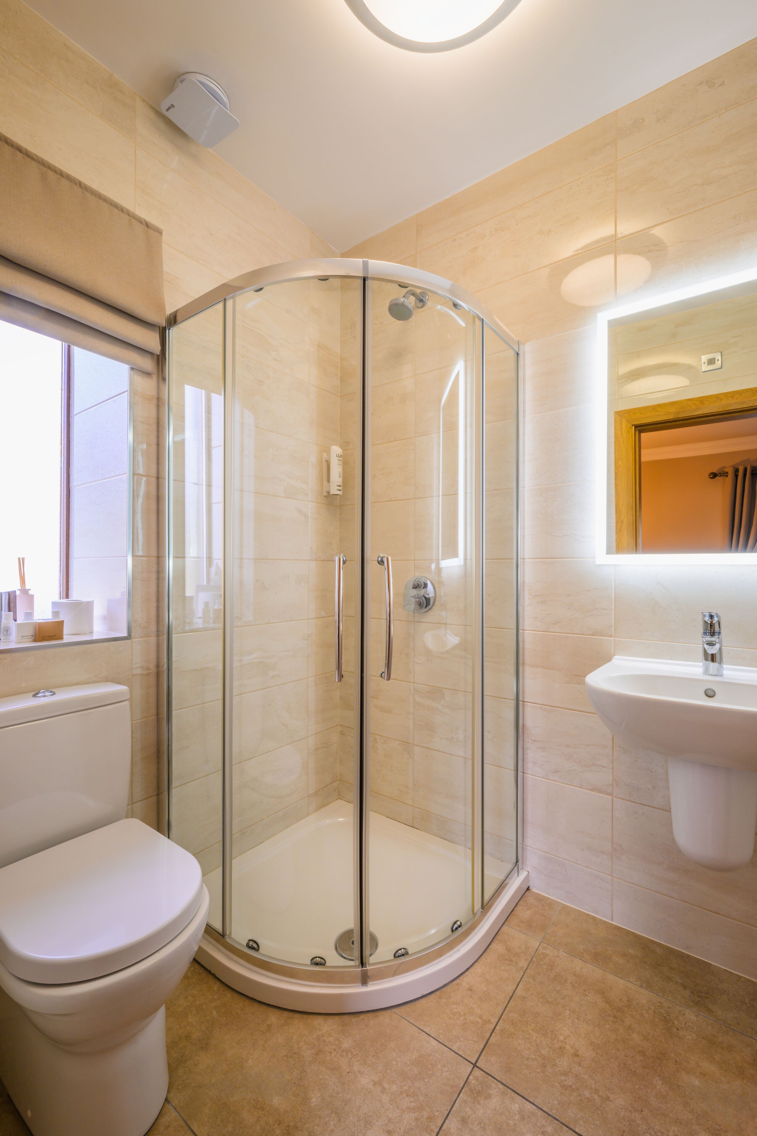 A modern bathroom with a glass-enclosed shower, a toilet, and a sink.