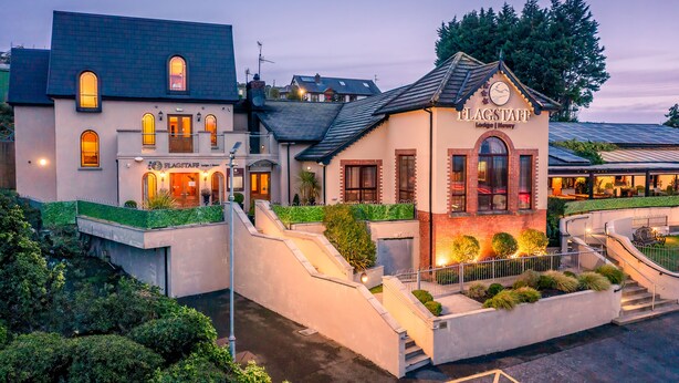 Un hotel con una entrada destacada, un balcón y una fachada bien iluminada.