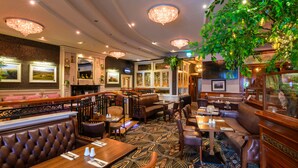 Un restaurante con diferentes opciones de asientos, incluyendo cabinas, mesas y una zona de bar.