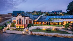 A lodge with a sign reading "FLAGSTAFF LODGE | Ledges | Narry." It features a modern design with a sloped roof, solar panels, and a reception area with outdoor seating. - Flagstaff Lodge (Newry)