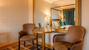 A hotel room with a round table, two chairs, a mirror, and a bed with pillows. - Flagstaff Lodge (Newry)