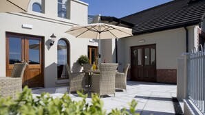 Un patio con muebles de mimbre, una mesa y una sombrilla.