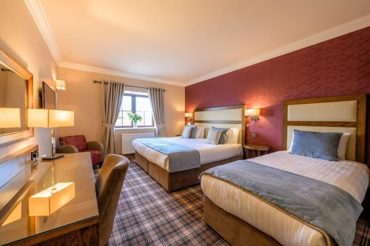 A hotel room with two beds, a desk, and a chair.