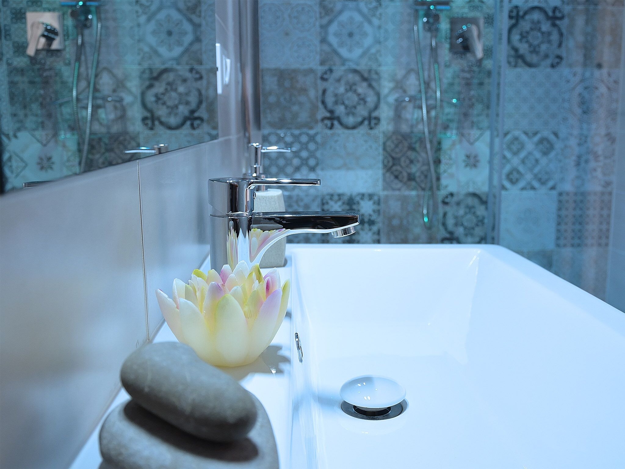 A bathroom with a white sink, a modern faucet, and a decorative lotus flower.