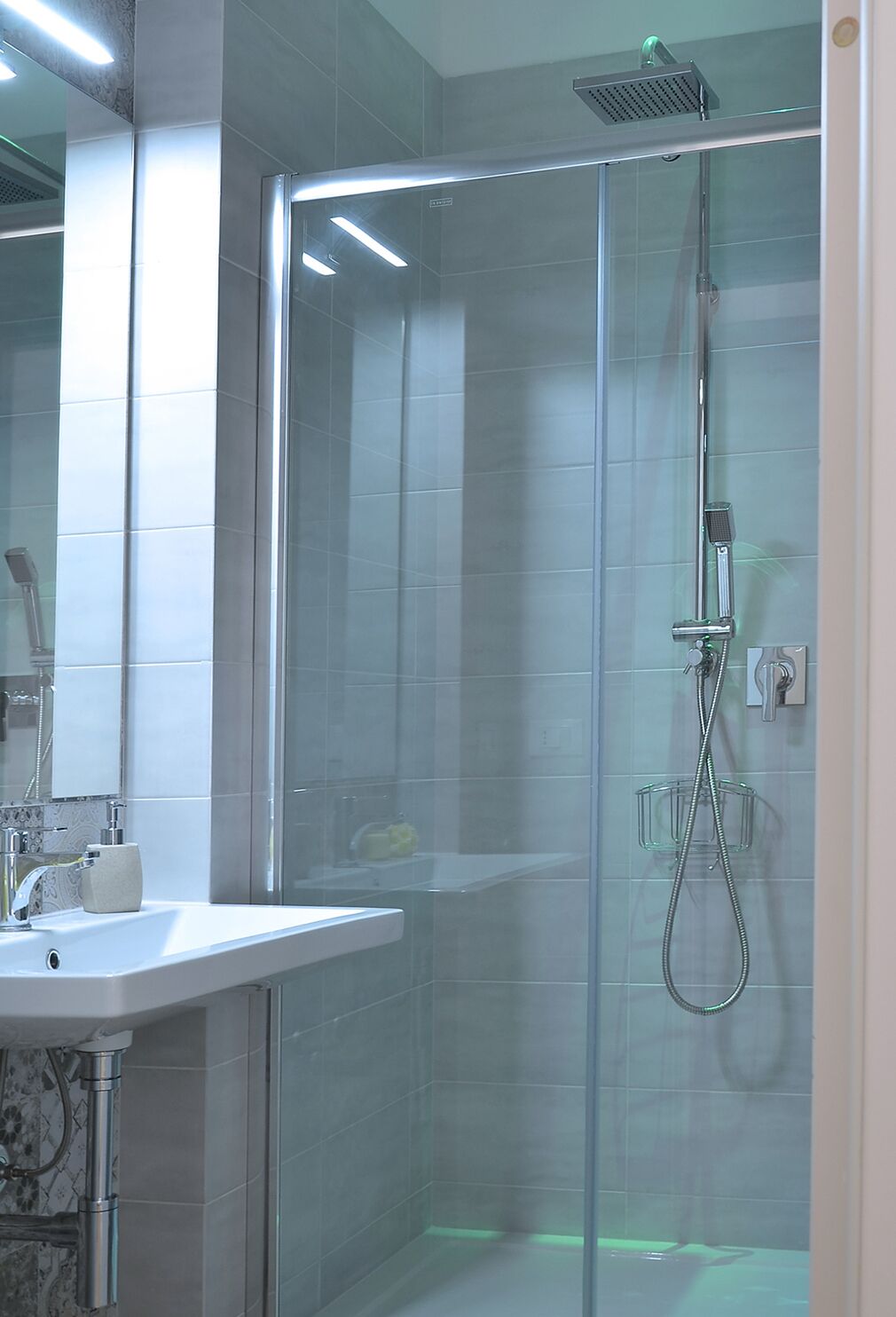 A modern bathroom with a glass-enclosed shower, a sink with a mirror, and a toilet.