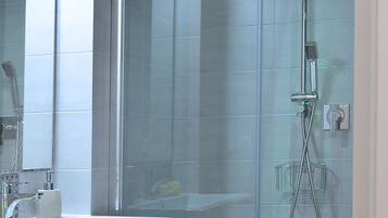 A modern bathroom with a glass-enclosed shower, a sink with a mirror, and a toilet.